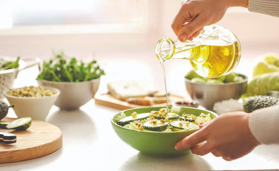 Hender heller over olivenolje over salat