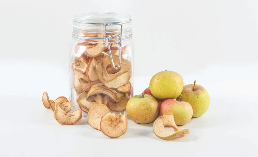 Tørkede epleskiver i glass med friske epler ved siden av